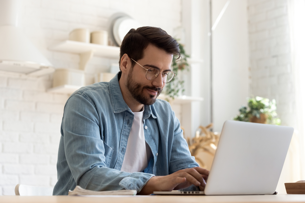 Focused,Young,Man,Wearing,Glasses,Using,Laptop,,Typing,On,Keyboard,